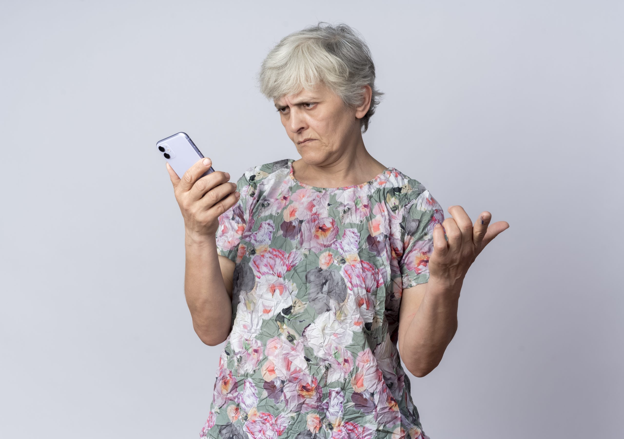 displeased elderly woman holding a phone on white background