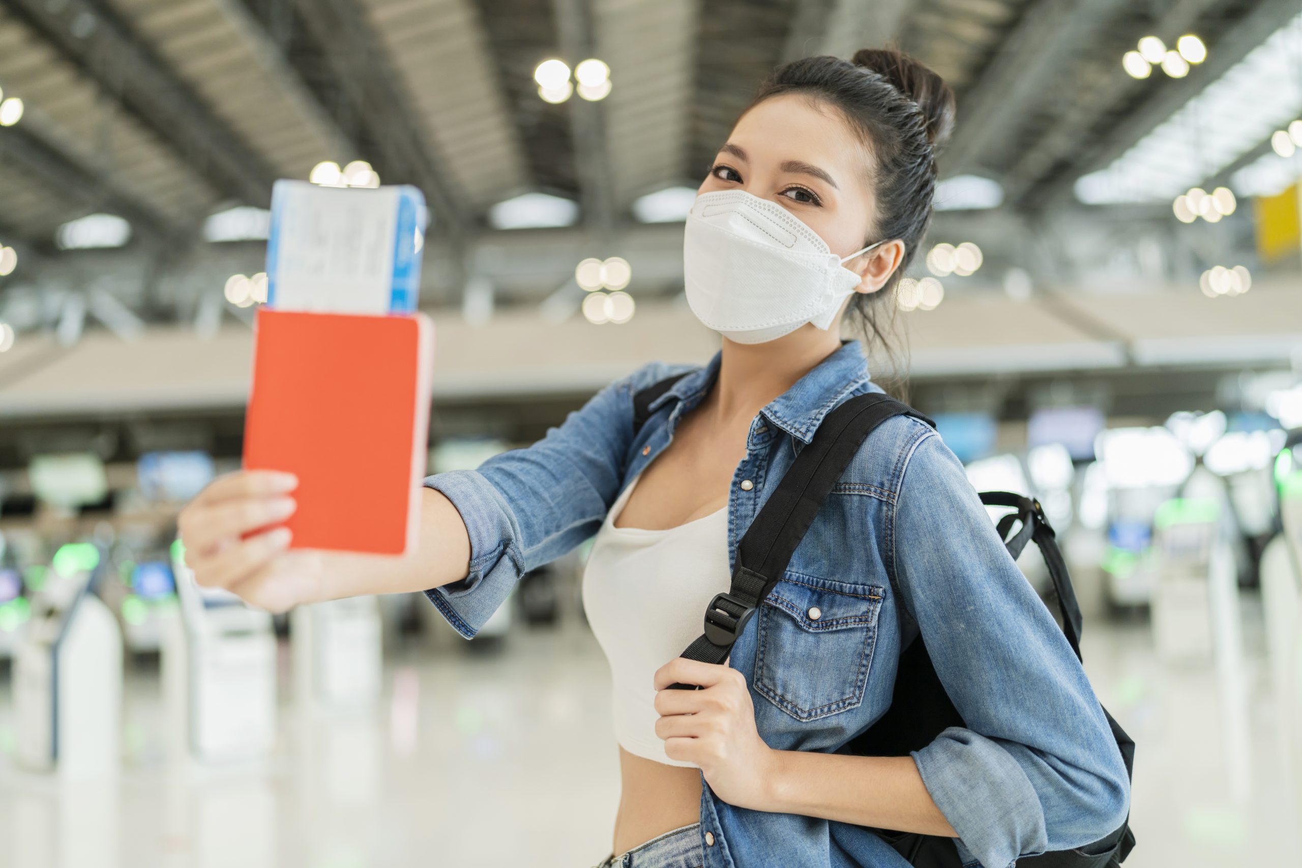 Woman holding plane ticket wearing mask