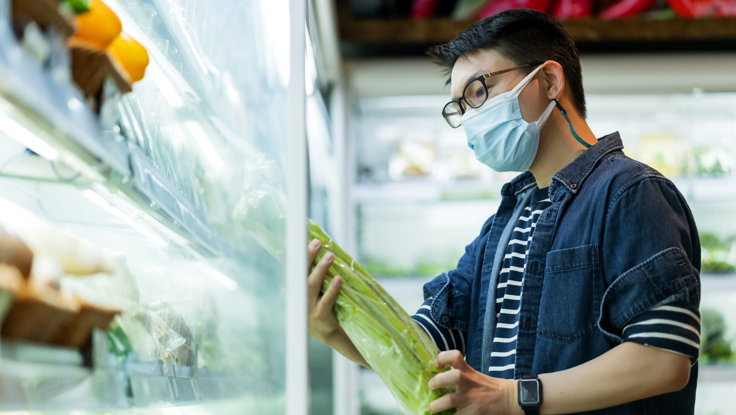 Asian man looking at a vegetable's price in a supermarket.