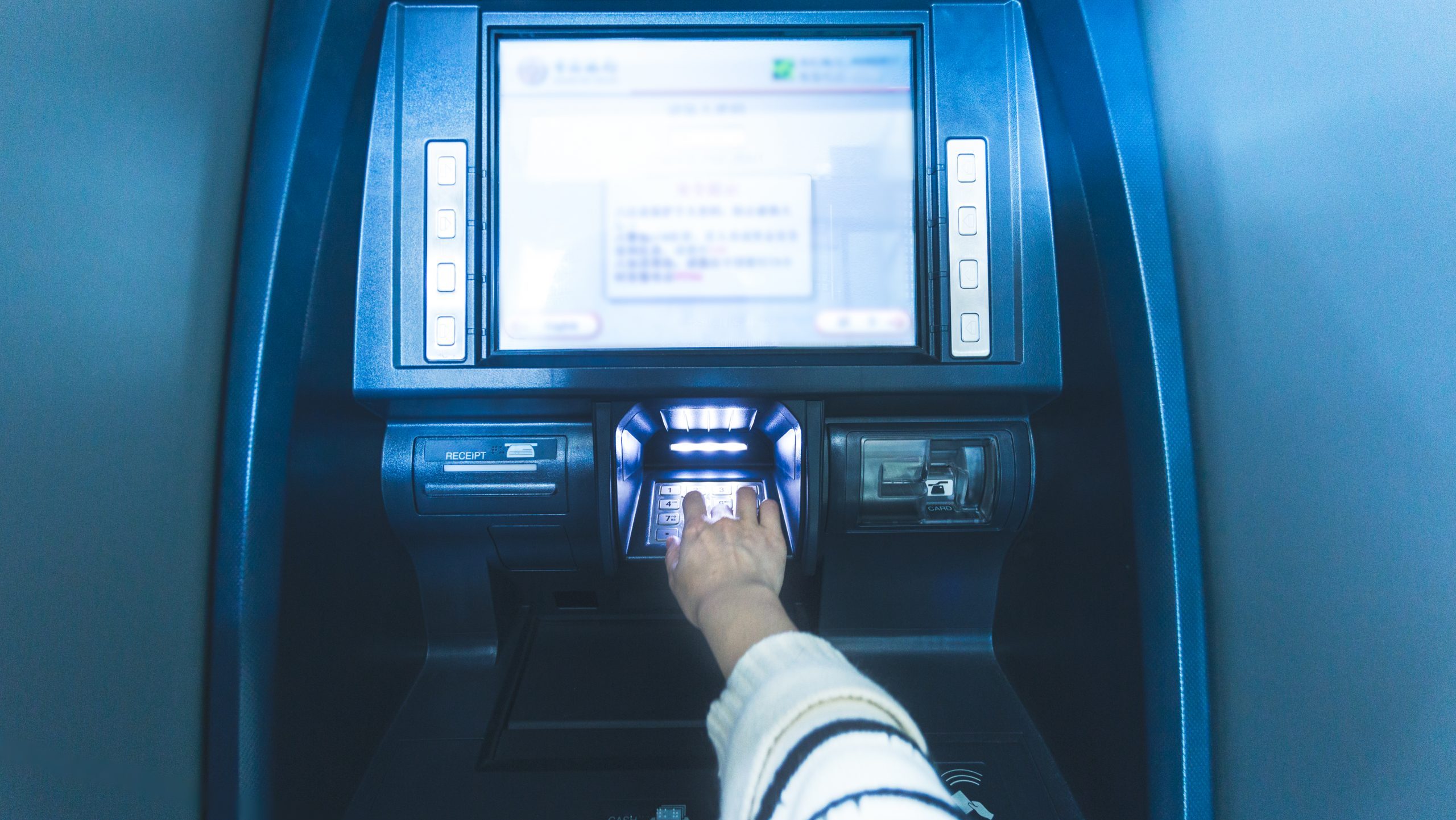 hand typing passcode on an atm