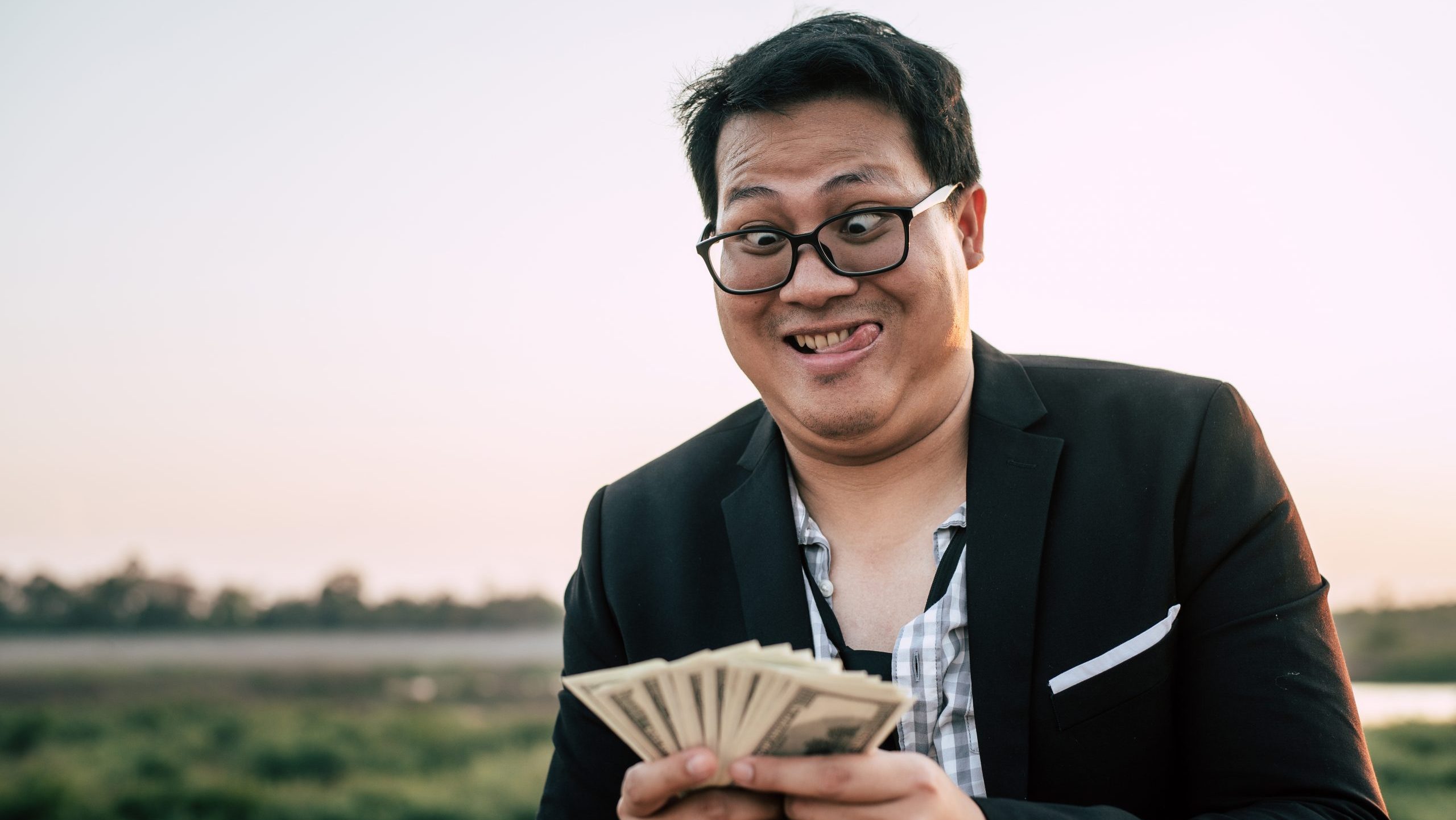 Man with silly facial expression holding a fan of money.