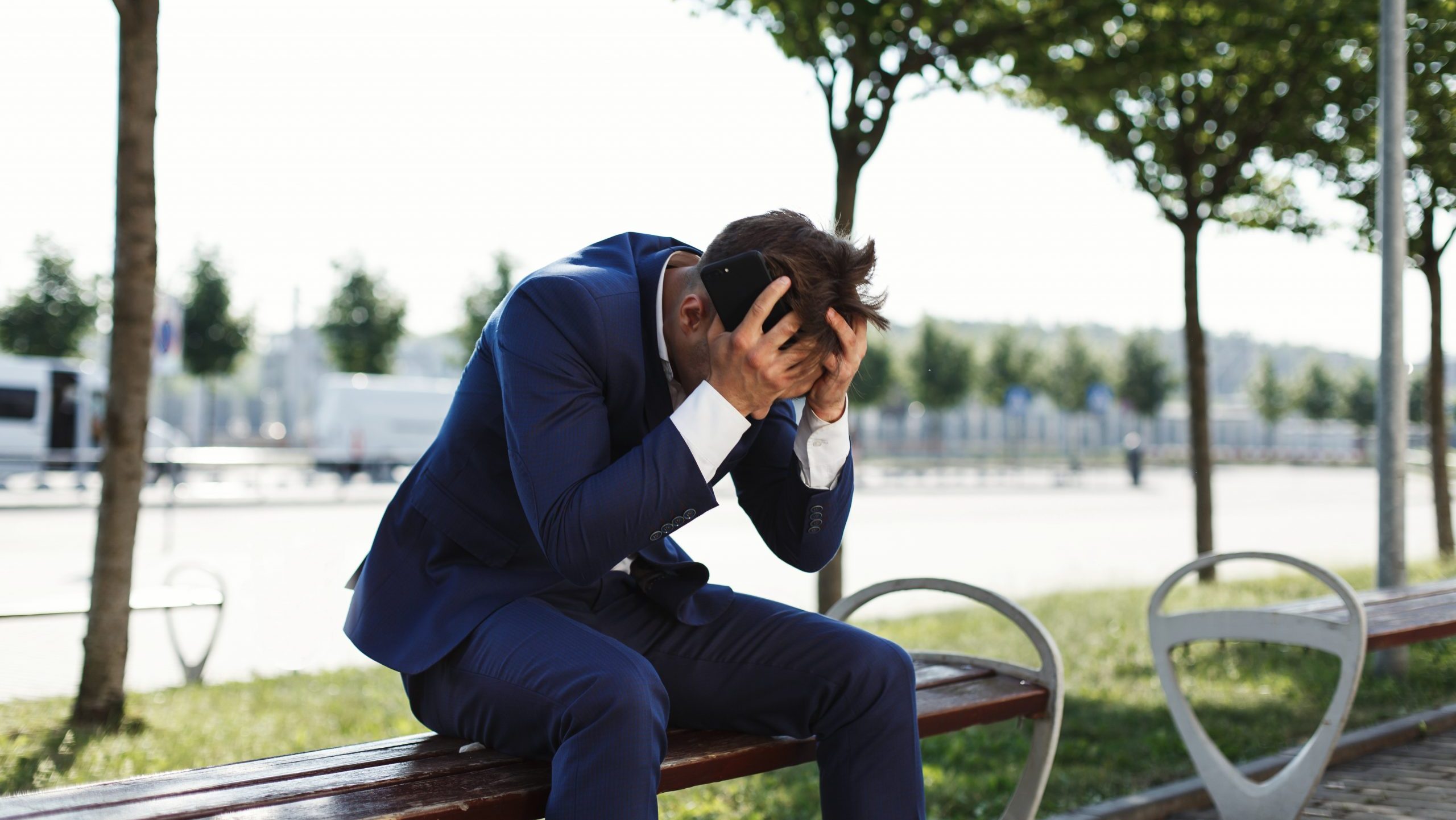 Sad businessman sitting on a bench outdoors.