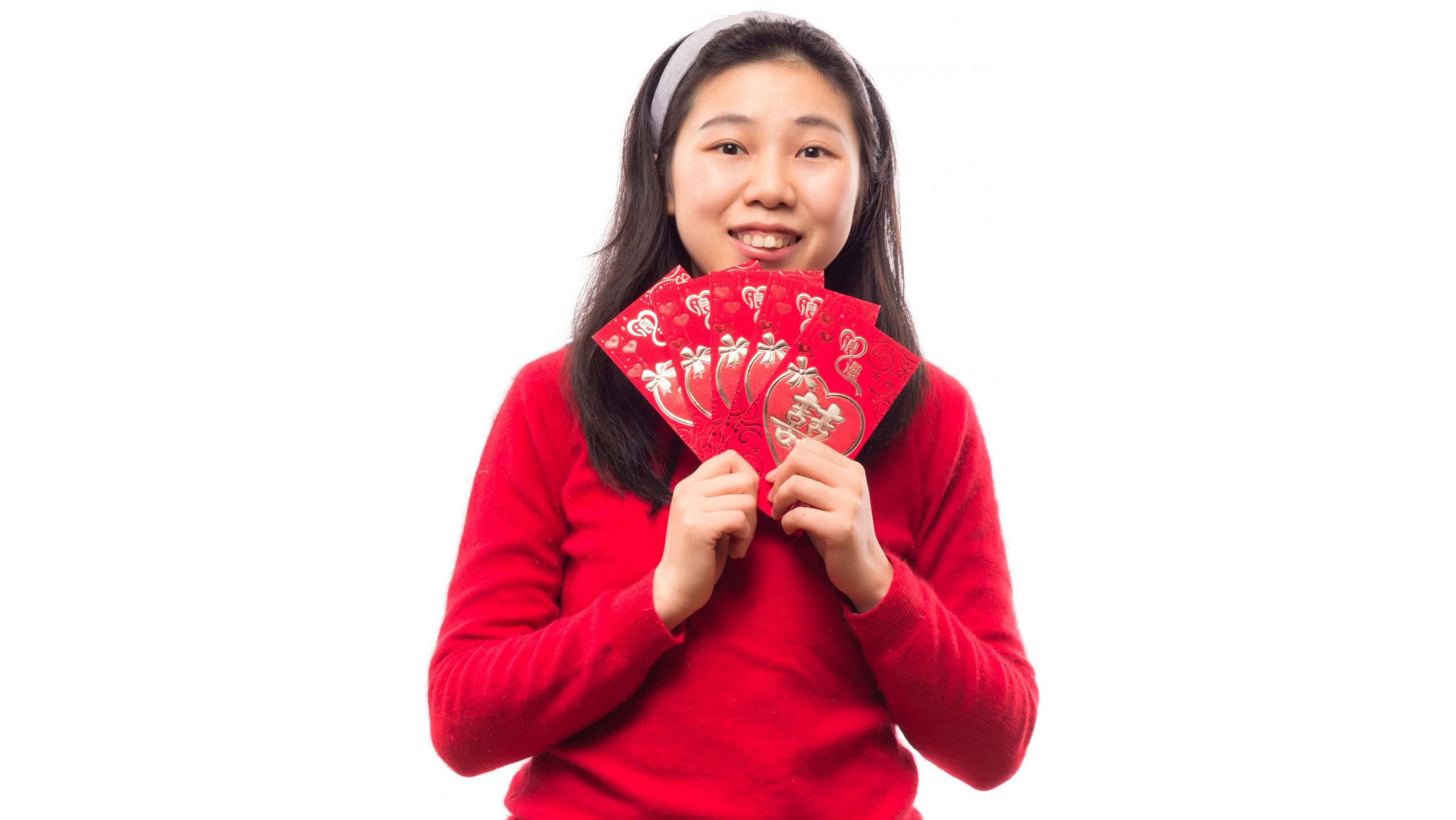 Young Asian woman in red sweater holding ang bao envelopes.