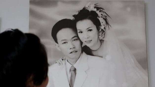 Mrs Soh holding a wedding portrait of her and her husband.
